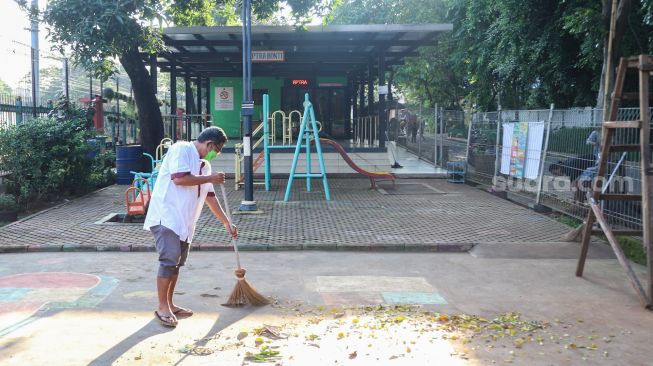 Petugas membersihkan dan merawat area bermain di RPTRA Kebon Melati, Jakarta Pusat, Jumat (25/6/2021). [Suara.com/Alfian Winanto]