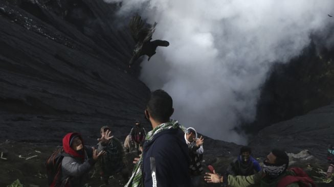 Warga berebut ayam sesaji yang dilemparkan ke kawah pada upacara ritual Yadnya Kasada di Gunung Bromo, Tengger, Probolinggo, Jawa Timur, Sabtu (26/6/2021). [ANTARA FOTO/Budi Candra Setya]