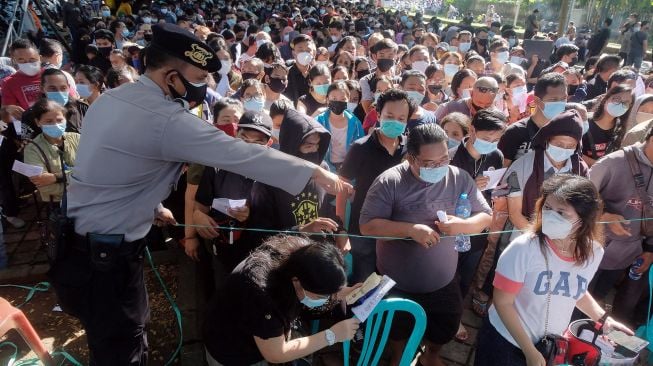 Anggota Polisi mengarahkan ribuan warga yang antre vaksinasi COVID-19 massal di Denpasar, Bali, Sabtu (26/6/2021).FOTO/Nyoman Hendra Wibowo