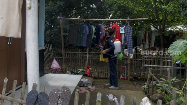 Warga menyemprotkan cairan disinfektan di Jalan Pangkalan 1, Bantargebang, Bekasi, Jawa Barat, Minggu (27/6/2021). [Suara.com/Dian Latifah] 