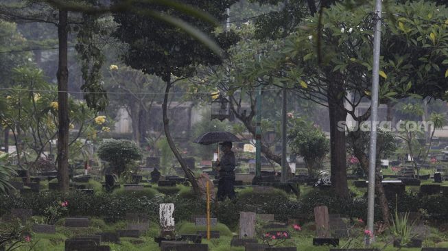 Petugas berjalan di Tempat Pemakaman Umum (TPU) Karet Bivak, Jakarta, Minggu (27/6/2021). [Suara.com/Angga Budhiyanto]