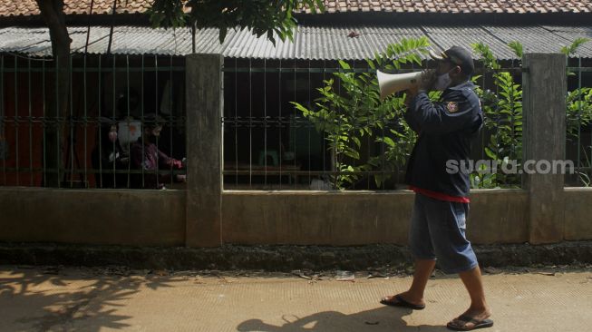 Warga memberi imbauan untuk menerapkan protokol kesehatan di Jalan Rawa Gula, Bantargebang, Bekasi, Jawa Barat, Minggu (27/6/2021). [Suara.com/Dian Latifah] 