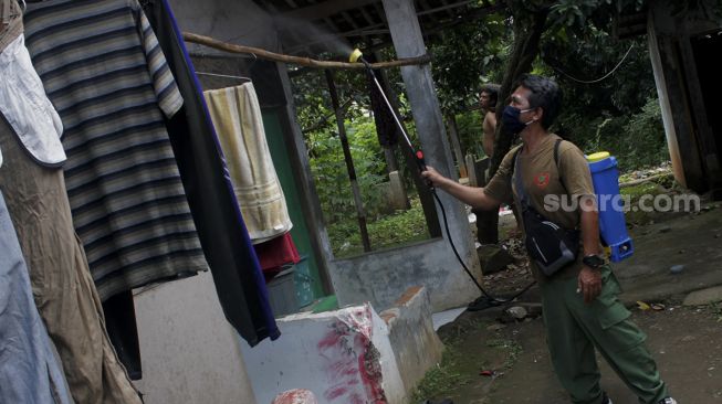 Warga menyemprotkan cairan disinfektan di Jalan Pangkalan 1, Bantargebang, Bekasi, Jawa Barat, Minggu (27/6/2021). [Suara.com/Dian Latifah] 