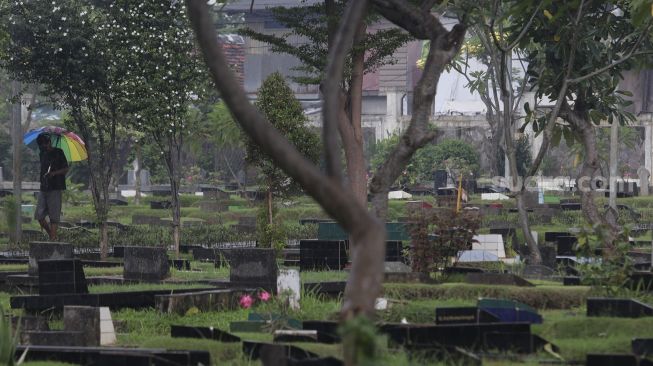 Petugas berjalan di Tempat Pemakaman Umum (TPU) Karet Bivak, Jakarta, Minggu (27/6/2021). [Suara.com/Angga Budhiyanto]