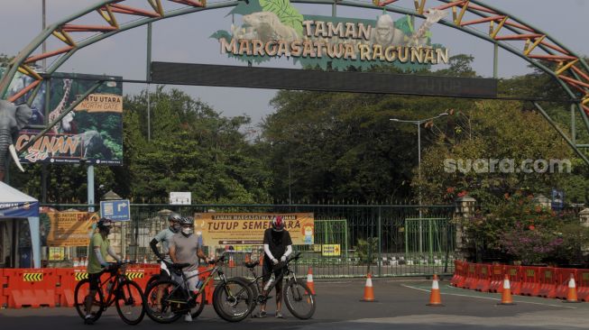 Pesepeda berada di depan gerbang utama Taman Margasatwa Ragunan, Jakarta, Minggu (27/6/2021). [Suara.com/Dian Latifah] 