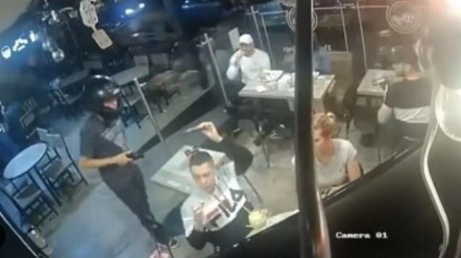 Momen ketika seorang pria tetap santuy makan ayam goreng saat ada perampokan.[CCTV via Daily Mail]