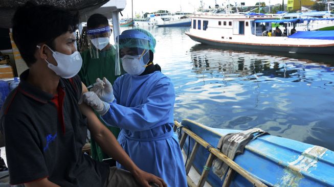 Tim medis TNI Angkatan Laut menyuntikkan vaksin COVID-19 kepada warga di atas kapal nelayan di Pelabuhan Paotere, Makassar, Sulawesi Selatan, Selasa (29/6/2021). [ANTARA FOTO/Abriawan Abhe]