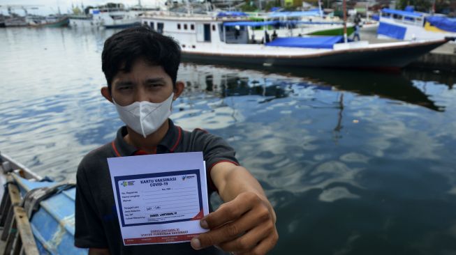 Warga memperlihatkan kartu vaksin usai mendapatkan suntikan vaksin COVID-19 di atas kapal nelayan di Pelabuhan Paotere, Makassar, Sulawesi Selatan, Selasa (29/6/2021). [ANTARA FOTO/Abriawan Abhe]