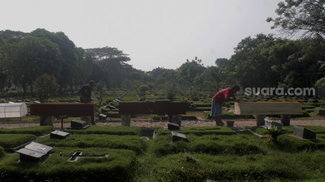 Pekerja menyelesaikan pembuatan peti mati di Yayasan Sahabat Duka, TPU Pondok Kelapa, Jakarta, Selasa (29/6/2021). [Suara.com/Dian Latifah]