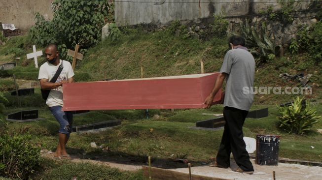 Pekerja menyelesaikan pembuatan peti mati di Yayasan Sahabat Duka, TPU Pondok Kelapa, Jakarta, Selasa (29/6/2021). [Suara.com/Dian Latifah]