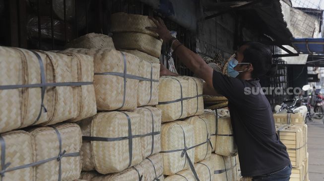 Pedagang merapikan besek dari anyaman bambu di Pasar Jatinegara, Jakarta, Rabu (30/6/2021). [Suara.com/Angga Budhiyanto]