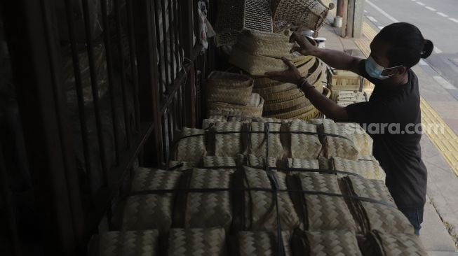 Pedagang merapikan besek dari anyaman bambu di Pasar Jatinegara, Jakarta, Rabu (30/6/2021). [Suara.com/Angga Budhiyanto]