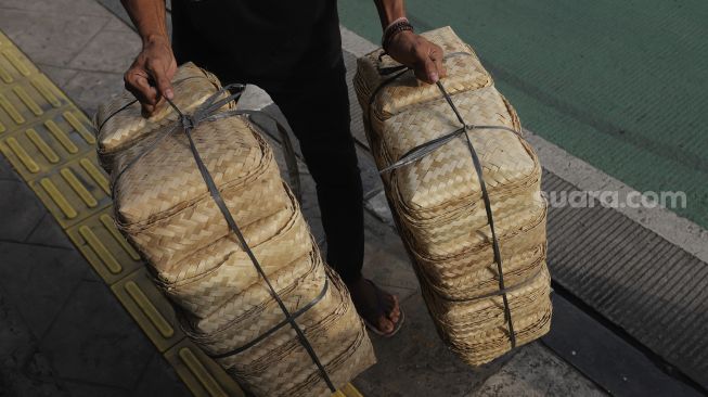 Pedagang membawa besek dari anyaman bambu di Pasar Jatinegara, Jakarta, Rabu (30/6/2021). [Suara.com/Angga Budhiyanto]