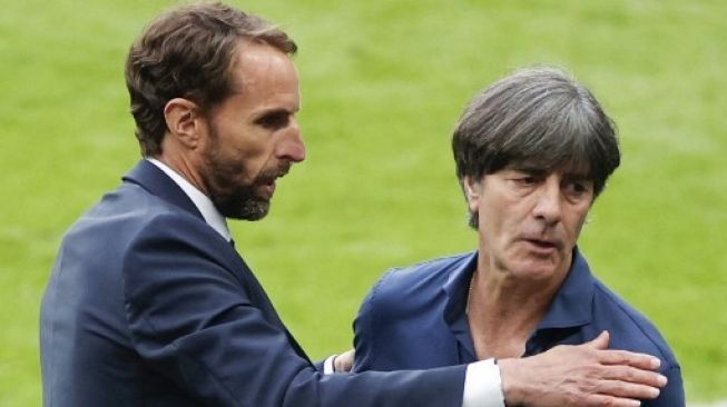 Pelatih Timnas Inggris Gareth Southgate menghampiri pelatih Jerman Joachim Loew usai kemenangan 2-0 The Three Lions atas Der Panzer di babak 16 besar Euro 2020 yang digelar di Stadion Wembley, Rabu (29/6/2021). [AFP]