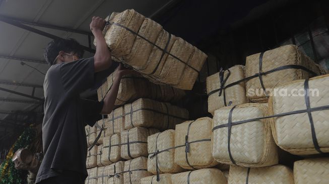 Pedagang merapikan besek dari anyaman bambu di Pasar Jatinegara, Jakarta, Rabu (30/6/2021). [Suara.com/Angga Budhiyanto]