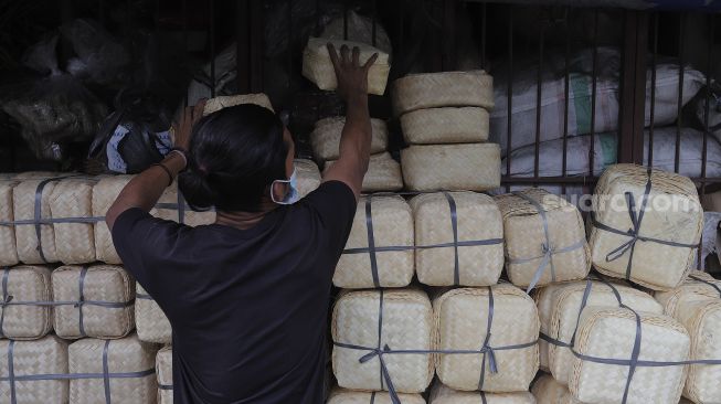 Pedagang merapikan besek dari anyaman bambu di Pasar Jatinegara, Jakarta, Rabu (30/6/2021). [Suara.com/Angga Budhiyanto]