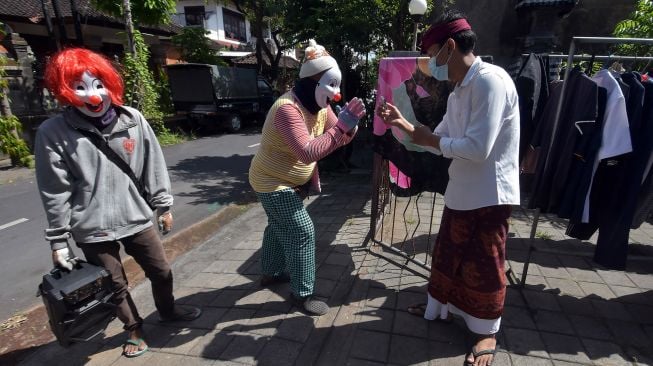 Dua warga perantauan menggunakan topeng badut saat mengamen di Denpasar, Bali, Rabu (30/6/2021).  ANTARA FOTO/Nyoman Hendra Wibowo