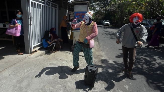 Dua warga perantauan menggunakan topeng badut saat mengamen di Denpasar, Bali, Rabu (30/6/2021).  ANTARA FOTO/Nyoman Hendra Wibowo