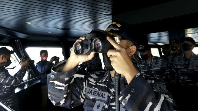 Komandan KRI Rigel-933 Letkol Laut (P) Jaenal Mutakim menggunakan teropong dalam pencarian korban KMP Yunicee yang tenggelam di Selat Bali, Jawa Timur, Jumat (2/7/2021). [ANTARA FOTO/Budi Candra Setya]