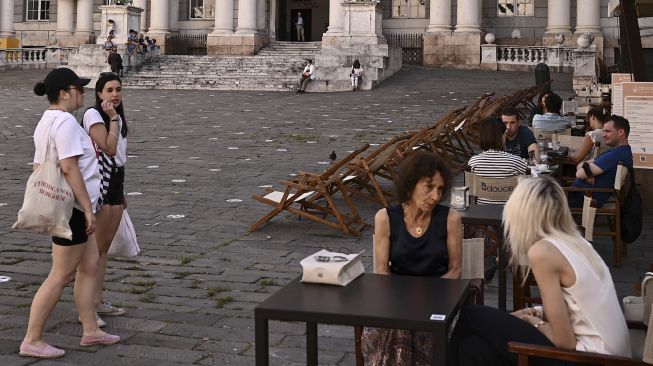 Warga berjalan dan mengobrol di dekat Palazzo Ducale, Genoa, pada (28/6/2021). [MARCO BERTORELLO / AFP]