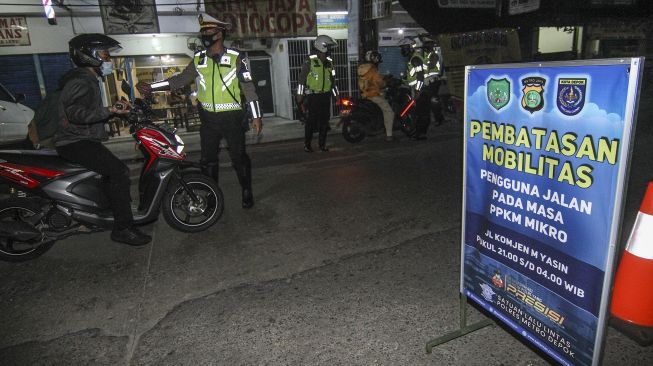 Petugas Polda Metro Jaya menghentikan pengendara yang masih melintas saat pembatasan mobilitas di Jalan Komjen M Yasin, Depok, Jawa Barat, Selasa (29/6/2021). [ANTARA FOTO/Asprilla Dwi Adha]
