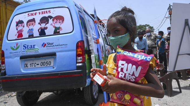 Seorang anak pergi dengan makanan ringan setelah memberikan sampel swab di New Delhi, India, pada (1/7/2021). [Prakash SINGH / AFP]