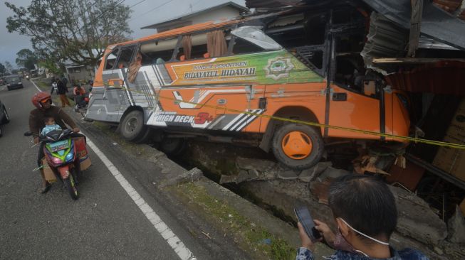 Pengendara melihat kondisi bus yang menabrak rumah akibat disenggol sebuah truk di Panyalaian, Kabupaten Tanah Datar, Sumatera Barat, Jumat (2/7/2021). [ANTARA FOTO/Iggoy el Fitra]