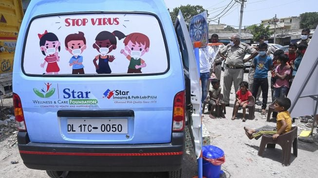 Anak-anak menunggu untuk memberikan sampel swab di luar sebuah mobil van di New Delhi, India, pada (1/7/2021). [Prakash SINGH / AFP]