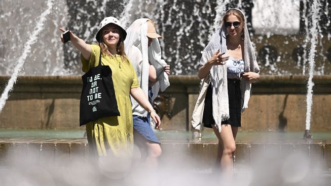 Warga berjalan tanpa mengenakan masker pelindung di alun-alun De Ferrari, Genoa, pada (28/6/2021). [MARCO BERTORELLO / AFP]