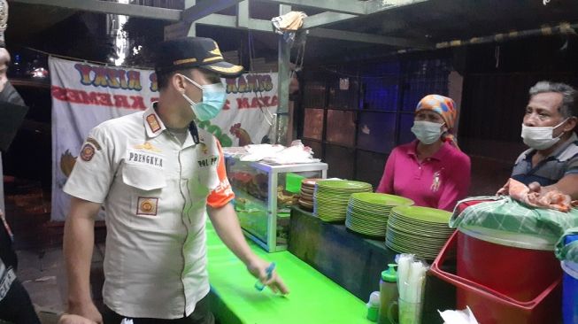 Satpol PP menindak sejumlah pedagang kaki lima yang melayani pembeli makan di tempat di kawasan Tebet Dalam, Jakarta Selatan, Sabtu (3/7/2021) malam. [Suara.com/Yaumal]