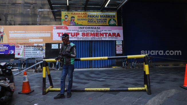 Seorang pengemudi ojek online menunggu pesanan di Pasar Tanah Abang, Jakarta Pusat, Sabtu (3/7/2021). [Suara.com/Alfian Winanto]