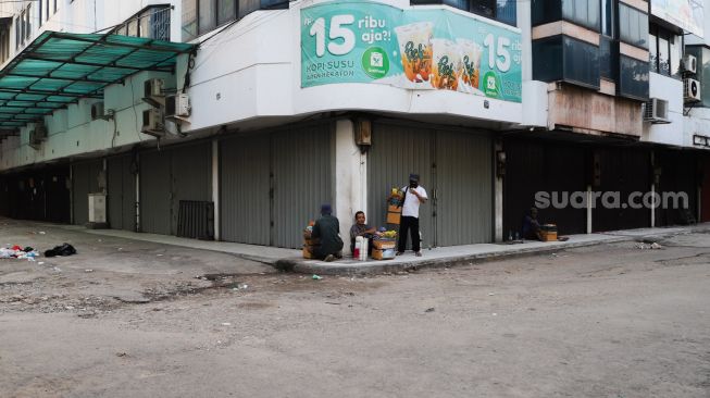 Pedagang asongan beristirahat di pelataran toko yang tutup di Pasar Tanah Abang, Jakarta Pusat, Sabtu (3/7/2021). [Suara.com/Alfian Winanto]