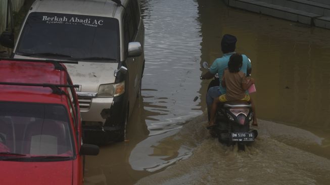 Pengendara sepeda motor melintasi banjir yang merendam pemukiman warga di Kampung Baru di Palu, Sulawesi Tengah, Sabtu (3/7/2021). [ANTARA FOTO/Mohamad Hamzah]