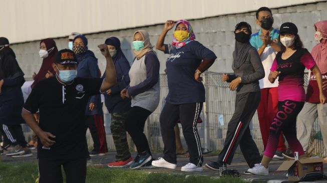 Warga mengikuti senam bersama di hari kedua PPKM Darurat di Jembatan Suramadu, Surabaya, Jawa Timur, Minggu (4/7/2021). [ANTARA FOTO/Didik Suhartono]