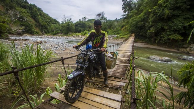 Pengendara melintas di jembatan yang rusak di Desa Datar Ajab, Kabupaten Hulu Sungai Tengah, Kalimantan Selatan, Minggu (4/7/2021). [ANTARA FOTO/Bayu Pratama S]