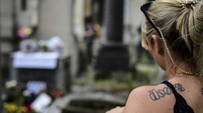 Orang-orang berkumpul di dekat makam pentolan The Doors Jim Morrison untuk memperingati 50 tahun kematiannya di pemakaman Pere Lachaise, Paris, pada (3/7/2021). [Martin BUREAU / AFP]