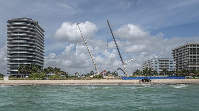 Mobil derek menandai cakrawala di tempat di mana pembongkaran terkontrol dari kondominium Champlain Towers South yang sebagian runtuh di Surfside, Florida, pada (5/7/2021). [Giorgio Viera / AFP]