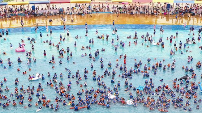 Foto udara menunjukkan orang-orang bersantai di kolam renang di Lianyungang, Provinsi Jiangsu Timur, China, pada (4/7/2021). [STR / AFP]