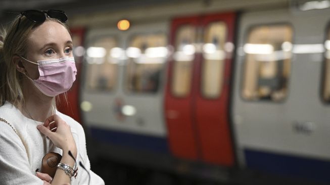 Penumpang mengenakan masker saat melakukan perjalanan dengan kereta bawah tanah Transport for London (TFL) di Kota London, pada (5/7/2021). [DANIEL LEAL-OLIVAS / AFP]