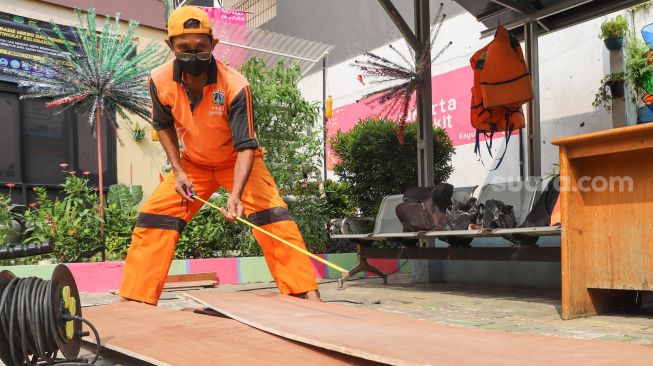 Petugas melakukan pengukuran saat membuat peti mati di Kantor Kelurahan Kayu Putih, Jakarta Timur, Selasa (6/7/2021). [Suara.com/Alfian Winanto]