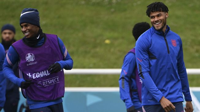 Pemain depan Inggris Marcus Rashford berbagi tawa dengan bek Inggris Tyrone Mings (kanan) selama sesi latihan di St George's Park, Burton-on-Trent, Inggris, pada (6/7/2021). [Paul ELLIS / AFP]