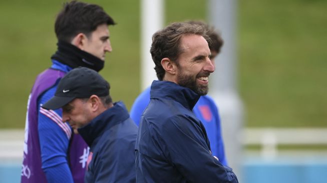Pelatih Inggris Gareth Southgate (kanan) tersenyum selama sesi latihan di St George's Park, Burton-on-Trent, Inggris, pada (6/7/2021). [Paul ELLIS / AFP]