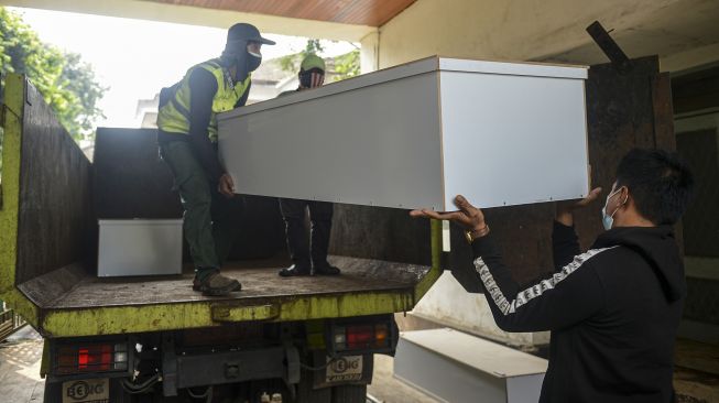 Pekerja mengangkut peti jenazah ke dalam truk untuk didistribusikan di TPU Petamburan, Jakarta Pusat, Selasa (6/7/2021). ANTARA FOTO/M Risyal Hidayat