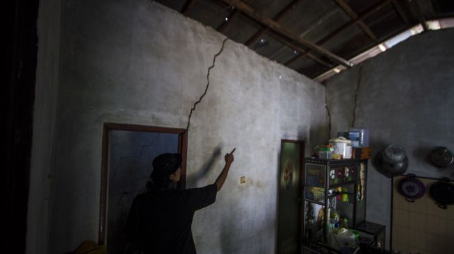 Warga melihat retakan dinding rumah akibat ledakan (blasting) dari tambang batu bara di Desa Pantai Cabe, Kabupaten Tapin, Kalimantan Selatan, Rabu (7/7/2021).  ANTARA FOTO/Bayu Pratama S