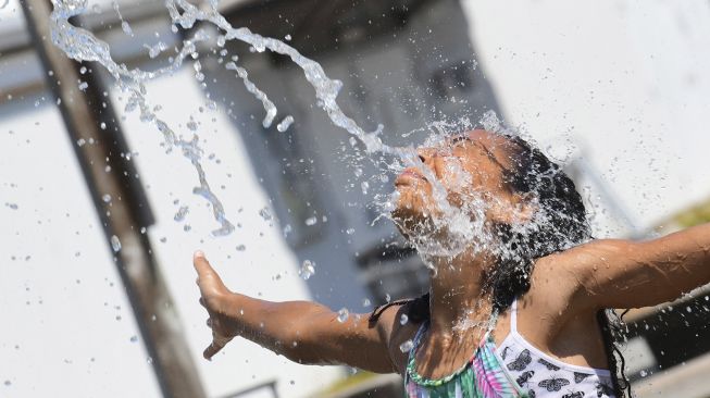 Seorang anak mendinginkan diri di taman air di Richmond, British Columbia, Kanada, pekan lalu. [Don MacKinnon / AFP]