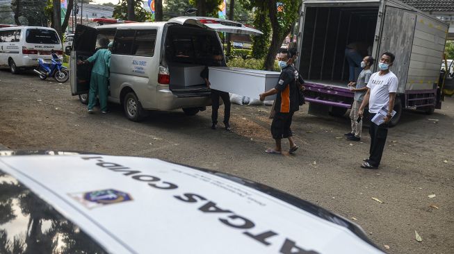 Pekerja mengangkut peti jenazah ke dalam ambulans untuk didistribusikan di TPU Petamburan, Jakarta Pusat, Selasa (6/7/2021). ANTARA FOTO/M Risyal Hidayat