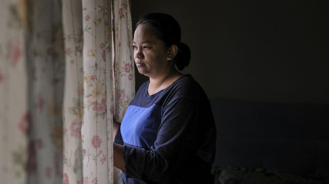 Seorang janda, Tilda Kalaivani melihat keluar jendela di apartemen sewaannya di Kuala Lumpur, Malaysia, pada (6/7/2021). [Mohd RASFAN / AFP]