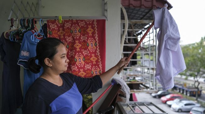 Seorang janda, Tilda Kalaivani melambaikan kemeja sebagai bendera putih untuk meminta bantuan setelah terdampak pandemi COVID-19 di apartemen sewaannya di Kuala Lumpur, Malaysia, pada (6/7/2021). [Mohd RASFAN / AFP]