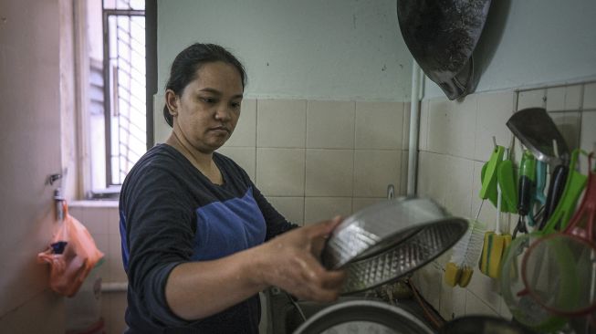 Seorang janda, Tilda Kalaivani mencuci piring di apartemen sewaannya di Kuala Lumpur, Malaysia, pada (6/7/2021). [Mohd RASFAN / AFP]