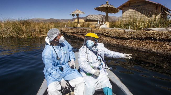 Petugas kesehatan diangkut ke Pulau Uros untuk menyuntik warga dengan vaksin COVID-19 Sinopharm di Danau Titicaca, Puno, Peru, pada (7/7/2021). [Carlos MAMANI / AFP]